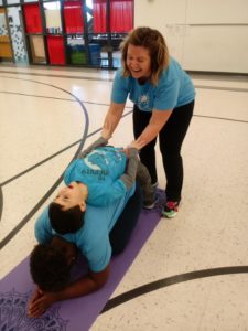 Instructors help a student with a yoga pose during Rhythm and Me